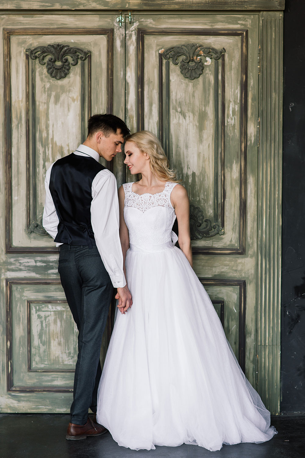 Cute wedding couple in the interior of a classic studio. They kiss and hug each other.